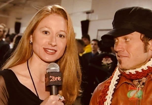 Bekka holding a mic interviewing TobyMac in a crowded room.