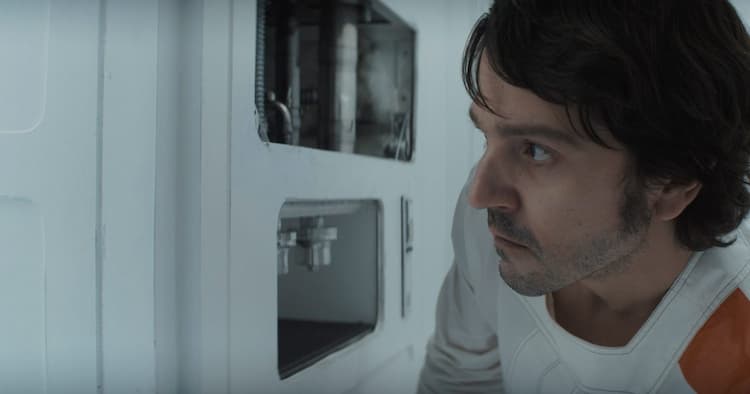 Cassian keeps a lookout as he tries to break a water pipe in the wall.