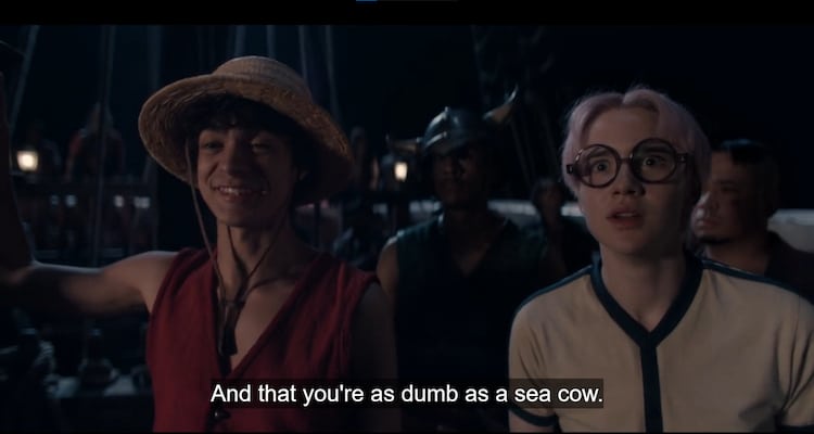 Luffy and Koby are on the deck of a ship at night. They are surrounded by pirates. Luffy has a joyful expression while Koby is terrified.